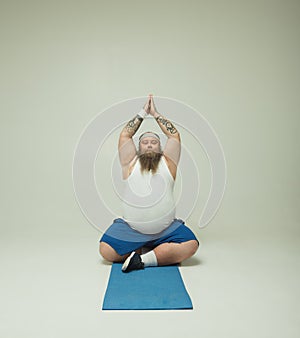 Tranquil male doing meditation on mat