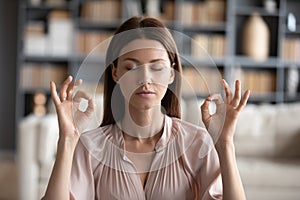 Tranquil mindful young woman managing stress at workplace.