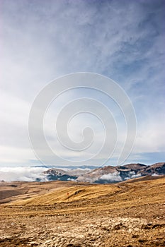 A tranquil mountain scene with clouds cover on a hill. Red guiding signs for snow