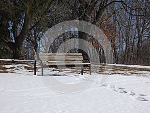 A tranquil park bench in a quiet park near Lake Story surrounded by snow