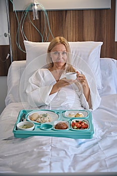 Tranquil patient having herbal beverage during lunchtime in ward