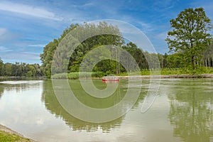 Tranquil river meandering through dense forest under serene sky with fluffy clouds, creating a peaceful natural landscape perfect