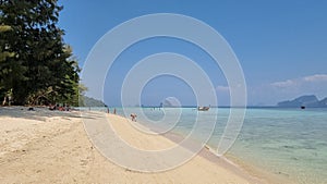 A tranquil sandy beach with a colorful boat peacefully floating in the crystal-clear water