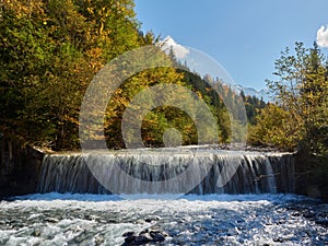 Tranquil scene of a cascading waterfall in a lush forest on a sunny day