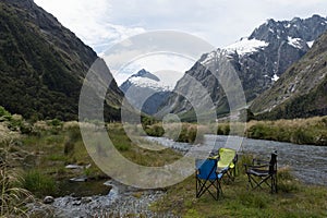 Tranquil scene of folding chairs in the green field on the background of majestic mountains