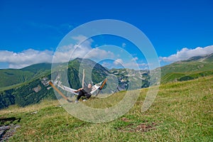 Tranquil Scene: Man Resting in Hammock, Admiring Green Mountain Landscape and Blue Sky
