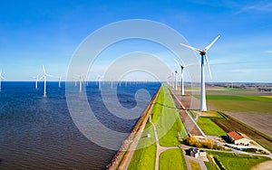 A tranquil scene of a row of windmills standing tall next to a calm lake in Flevoland, Netherlands