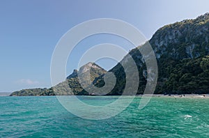 Tranquil scene of a tropical beach with lush mountains under a clear sky