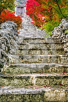 Tranquil Scenery of Japanese Shrine With Garden Near Stony Stairs and Seasonal Red Maple Trees At Fall in Japan