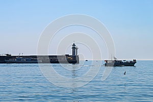 A tranquil seascape. Small pleasure boats on the background of the white tower of the old lighthouse. Yalta, Crimea.