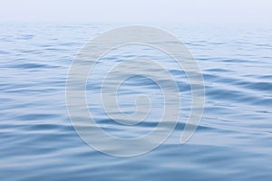 Tranquil and serene ocean surface. Calm and relaxed mirror-like blue sea background.