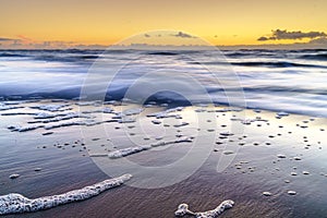 Tranquil sunset on the beach with beautiful reflections on the water, North Sea, Netherlands