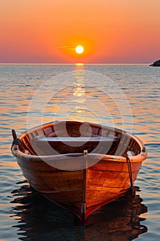 Tranquil sunset view over ocean with serene empty wooden rowboat on still calm water