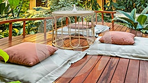 Tranquil sustainable relaxation zone with soft cushions and small table on wooden deck