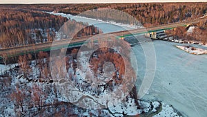 Tranquil winter landscape with road bridge at sunset, aerial view.