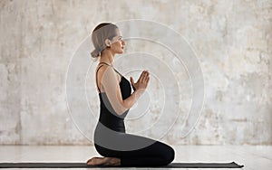 Tranquil woman makes Namaste gesture doing Seiza exercise Vajrasana asana