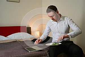 Tranquil young businessman eating in his hotel room