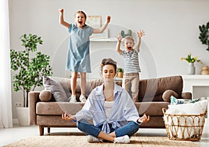 Tranquil young mother practicing yoga to stay calm with mischievous kids at home photo