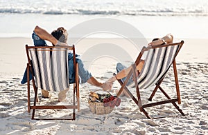 Tranquility is what were after. Rearview shot of a middle aged couple sitting in their beach chairs on the the beach.