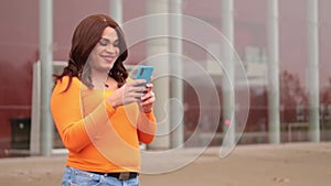 Trans woman using cellphone and laughing. Copy space
