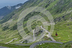 Transfagarasan - High altitude winding road in Carpathians mountains panorama with running cable car . Aerial view.