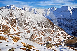 Transfagarasan road hairpins covered with snow in Winter, with snowy peaks in the background, on a sunny day. Famous mountain road