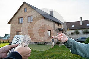 Transfer money and key home in front of home. Real estate, moving home or renting property concept