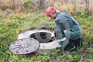 Transfer of water meter readings. A municipal worker inspects a water meter in a water well, checking the readings