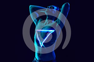 Transformation. Handsome young man with muscular body posing shirtless with neon triangle digital light reflection on