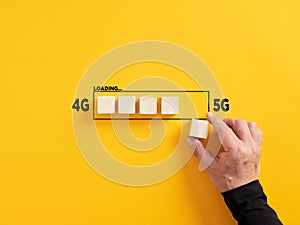 Transformation of wireless network connection technology from 4G to 5G. Hand places a wooden cube to the loading bar with the