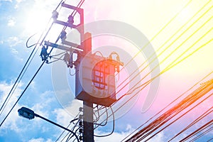 Transformer High voltage electricity pole and power line with blue cloudy sky background.