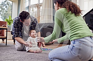 Transgender Family Encouraging Baby To Take First Steps In Lounge At Home