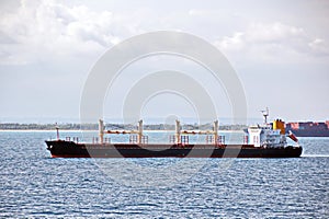 Transhipment terminal for discharging cement cargo by shore cranes. A view of berths with cargo ships and the water area of the po