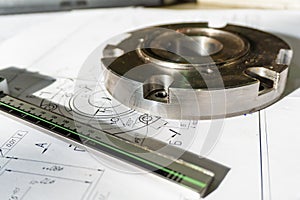 The transition flange after processing lies on the technical drawing. Next to the part is the measuring tool, a caliper