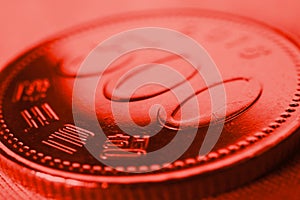 Translation: Bank of Korea. 500 won coin close-up. Red tinted background or wallpaper on an economic, financial or banking theme.