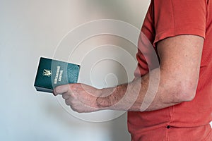 Translation: military id. Civil man in red t-shirt holds ukrainian military id in hand.