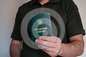 Translation: military id. Officer holding ukrainian military id in hand.