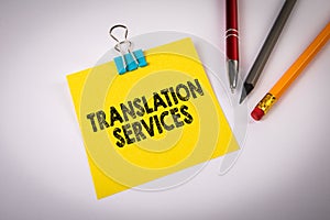 TRANSLATION SERVICES. Text on yellow sticky note. White office desk