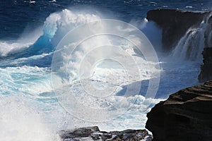 Translucent ice-blue waves crashing onto cliffs