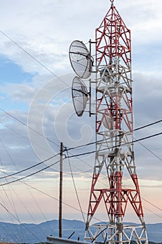 Transmission lines passing through broadcast tower. Satellite disk mounted in the microwave antenna. Wooden electrical post connec