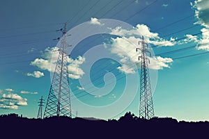 Transmission towers carrying high voltage electric power lines. Silhouettes of electricity pylons in the field