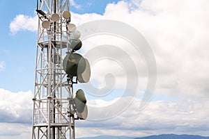 Transmitters and aerials on telecommunication tower with cloudy blue sky