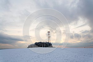 Transmitters and aerials on telecommunication tower, sunset in snowy country