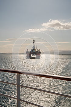 Transocean Leader oil platform at Invergordon during sunset, cruise ship railing in front, vertical shot