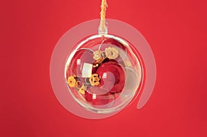 Transparent ball with a red christmas balls inside on red background