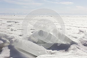 Transparent blue ice hummocks on lake Baikal shore. Siberia winter landscape view. Snow-covered ice of the lake