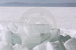 Transparent blue ice hummocks on lake Baikal shore. Siberia winter landscape view. Snow-covered ice of the lake