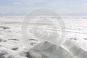Transparent blue ice hummocks on lake Baikal shore. Siberia winter landscape view. Snow-covered ice of the lake