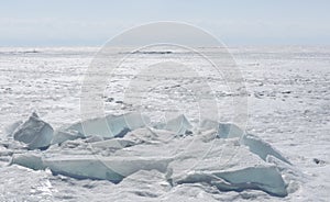 Transparent blue ice hummocks on lake Baikal shore. Siberia winter landscape view. Snow-covered ice of the lake. Big