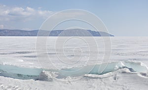 Transparent blue ice hummocks on lake Baikal shore. Siberia winter landscape view. Snow-covered ice of the lake. Big